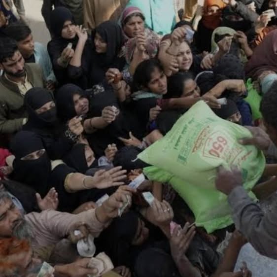 A volunteer handing a ration bag to a family in the crowd
