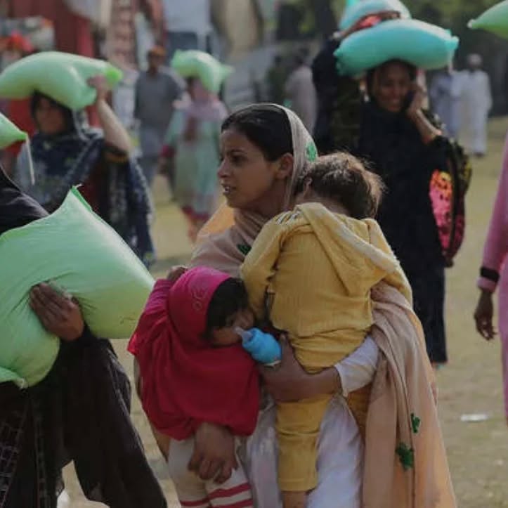 A mother carrying her two children at the distribution ground
